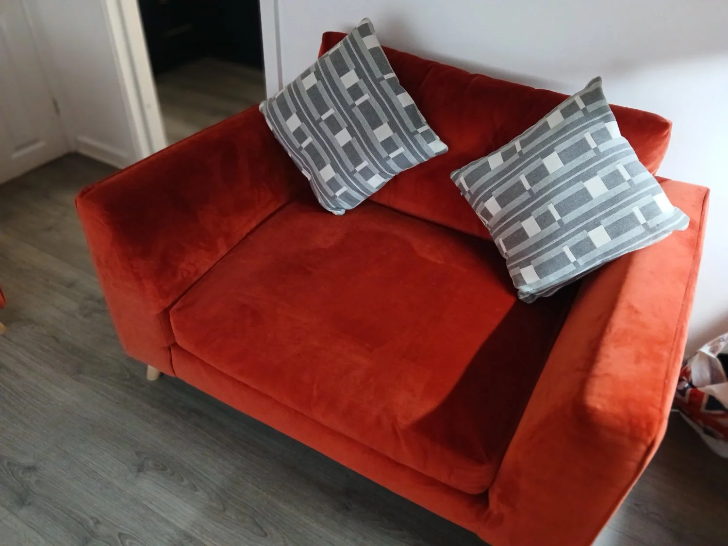 Two Rust orange fabric two-seater sofa with rounded arms and timber feet